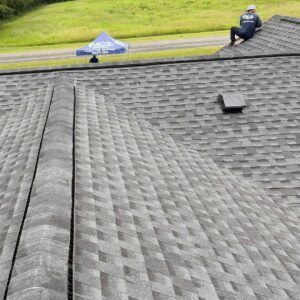 Roofer installing cap shingles and making final adjustments at roof edge.