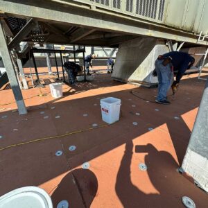 Roofing team member fastening insulation to the metal decking on a flat roof.