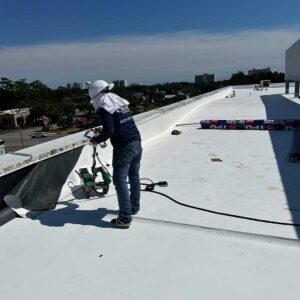 Roofer heat-welding wall flashing to TPO roof membrane for water-tightness.