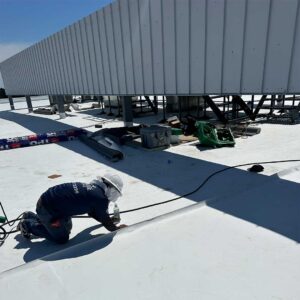 Roofing crew cleaning and prepping membrane seams prior to welding.