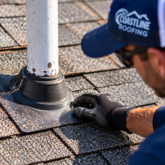 Coastline Roofing contractor inspecting pipe boot flashing on an asphalt shingle roof