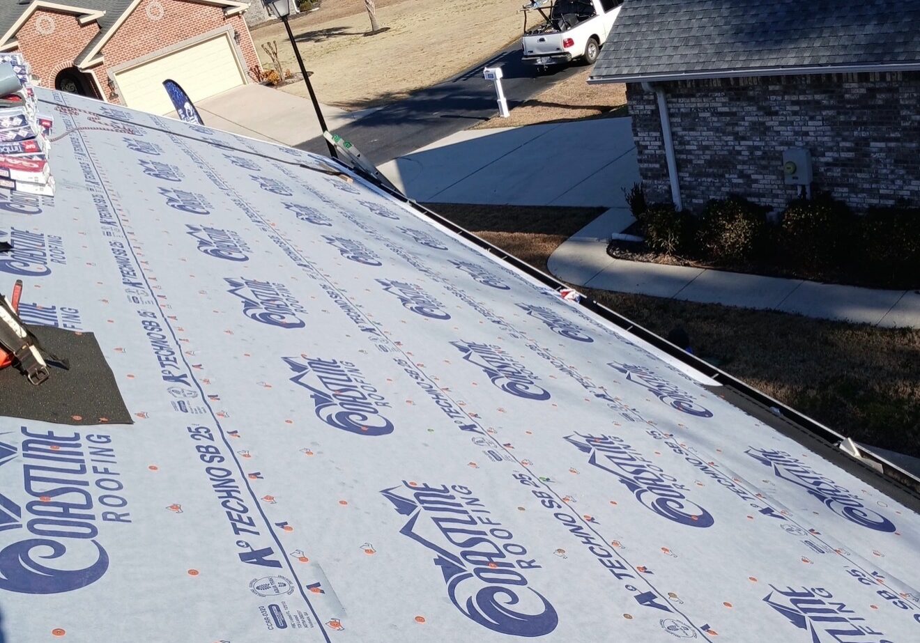 Coastline Roofing crew installing underlayment during a roof replacement