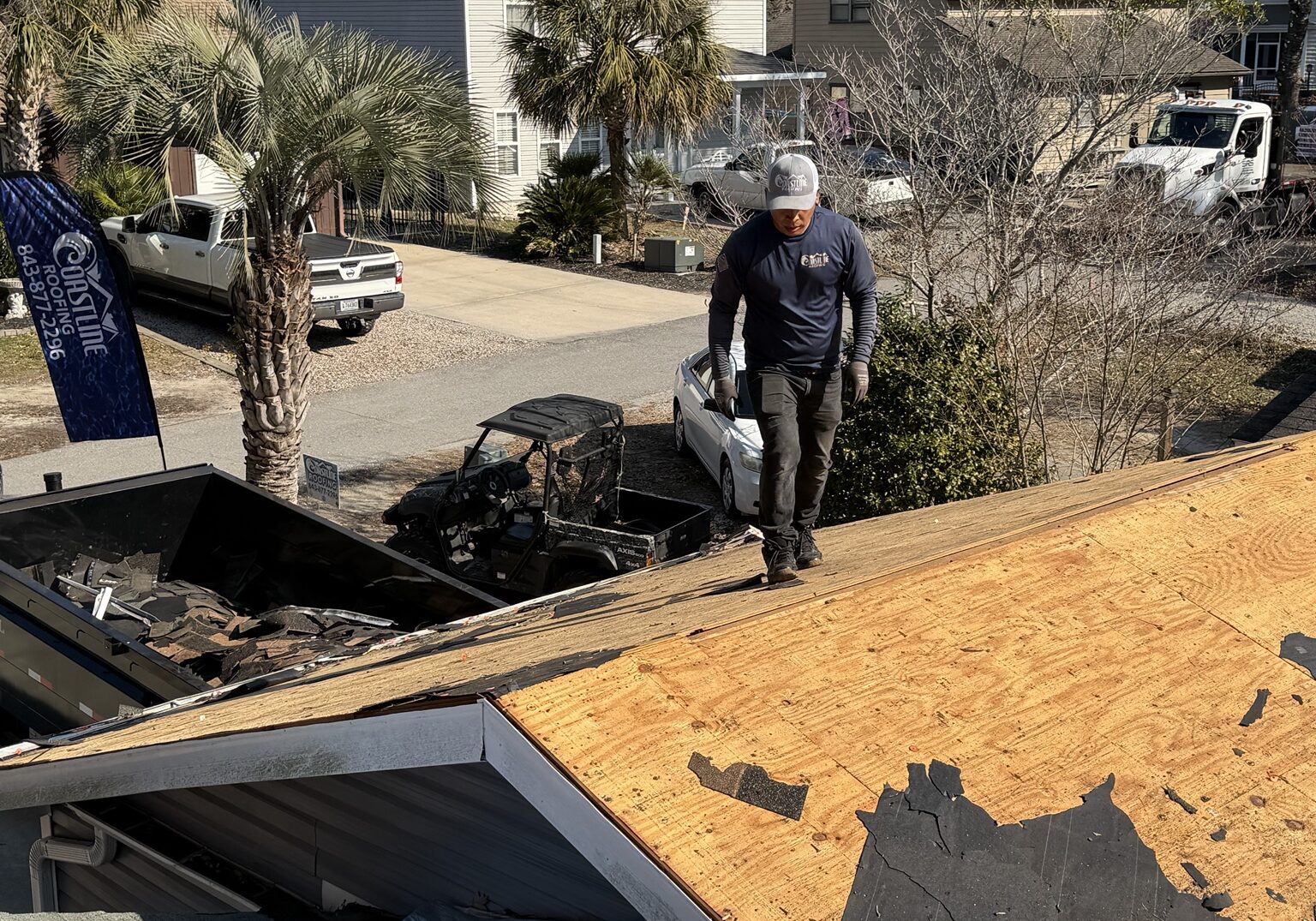 Coastline Roofing crew inspecting exposed roof decking during a roof replacement